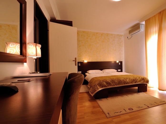Cozy bedroom with a double bed and desk at the Petrovac hotel, Montenegro. Bright interior with decor.