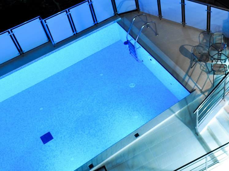 Open-air pool with night lighting and a relaxation area at a hotel in Petrovac, Montenegro. Top view of the terrace with furniture.