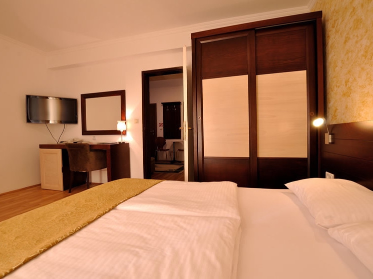 Bedroom in a hotel in Petrovac, Montenegro: double bed, wooden sliding wardrobe, desk, and TV in the room.
