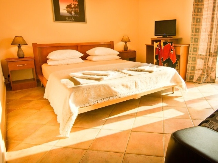 Cozy bedroom with a double bed at the Sutomore Hotel, Montenegro: tiled floor, bedside tables, and TV area.