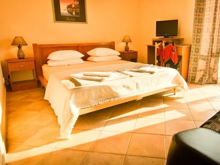 Bedroom featuring a wooden bed with white linens, bedside tables with lamps, and a TV on a dresser.