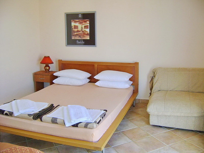 Bedroom in a hotel in Sutomore, Montenegro: double bed, armchair, bedside table, and tiled floor.