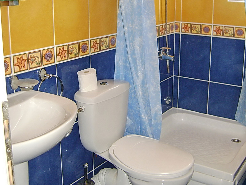 Bathroom in a hotel in Sutomore, Montenegro: shower cabin, plumbing fixtures, and bright floral-patterned tiles.