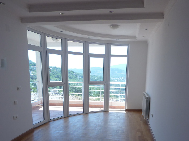Bright living room with panoramic windows and mountain views in a villa, Dobrota, Montenegro. Parquet flooring and modern design.