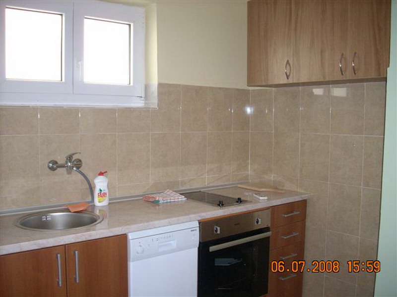 Kitchen in a house in Sutomore, Montenegro: built-in cabinetry, stove, oven, dishwasher, and tiled backsplash.