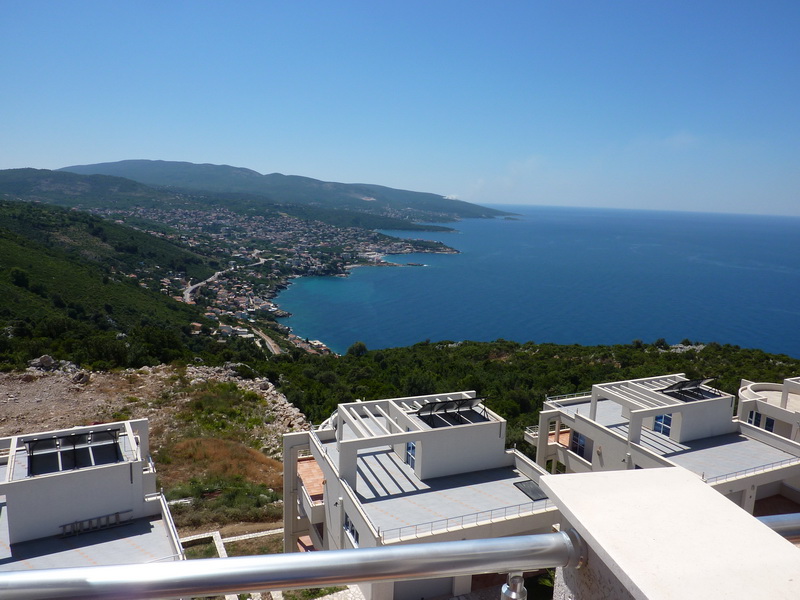 View from the villa balcony in Dobra Voda, Montenegro: a panorama of the Adriatic Sea, mountains, and modern houses with terraces.