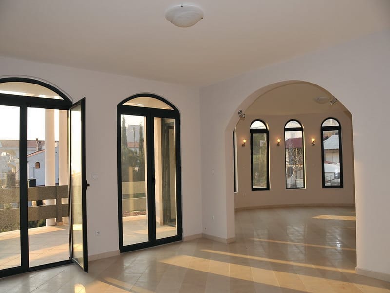 Bright living room with arched windows and access to the terrace in a house, Uteha, Montenegro. High-quality interior finishes.