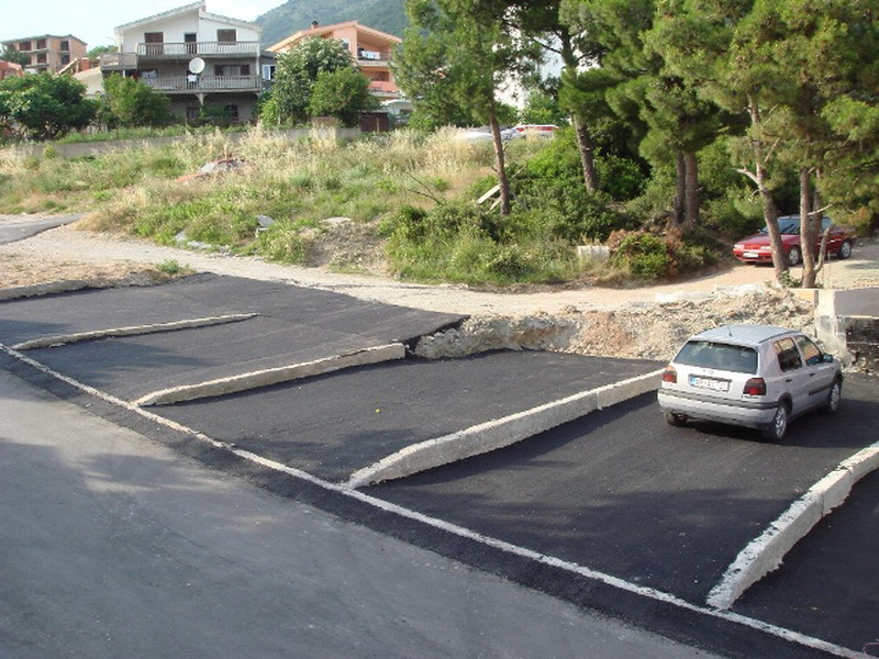Paved parking lot by the house in Bar, Montenegro, with marked parking spaces and mountain views.