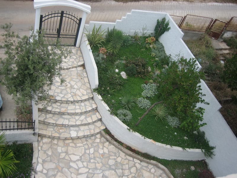 Well-kept garden and stone staircase by the house in Utjeha, Montenegro: top view of the landscaping and entrance area.