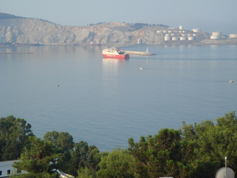 Panoramic view of the sea and port in Bar, Montenegro: a seascape with a ship and mountains in the background.