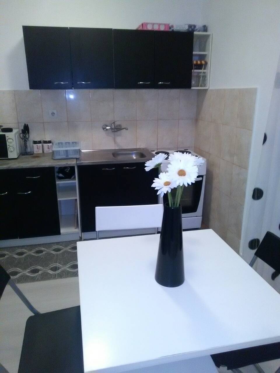 Kitchen with a black cabinet set and dining table in a house, Shushan, Montenegro. Modern interior with white finishes.