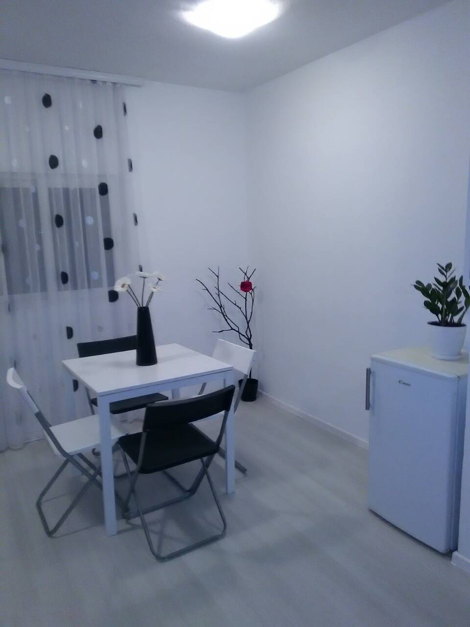 Bright kitchen in a house in Shushan, Montenegro: dining area with a white table, chairs, and a refrigerator in the interior.