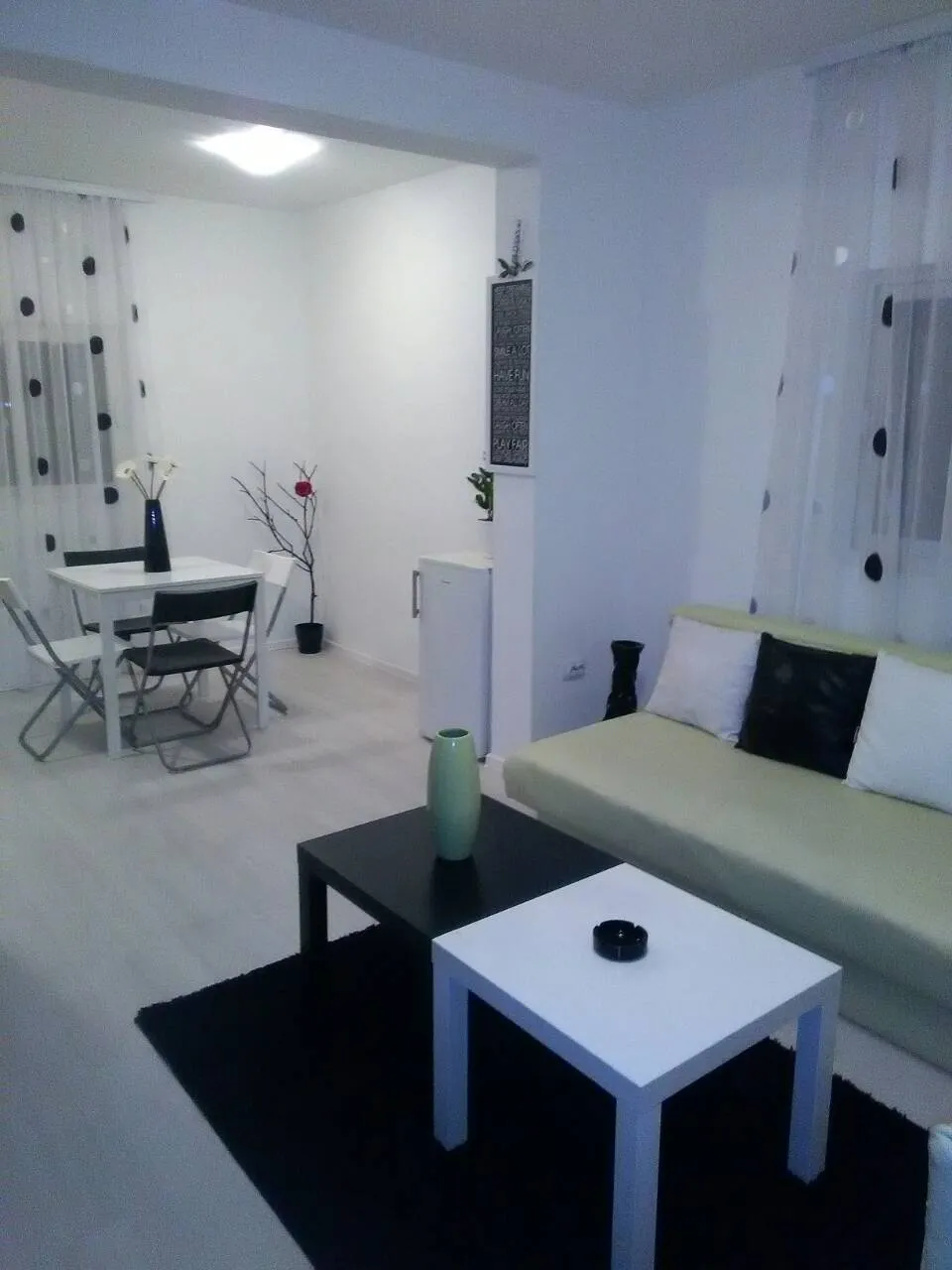 Living room with a sofa, coffee tables, and a dining area visible in the background.