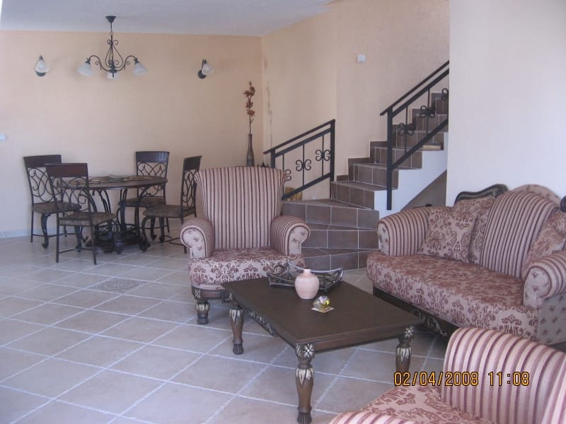 Living room with soft furniture, dining area, and staircase in a house in Utjeha, Montenegro: interior with tiled floor.