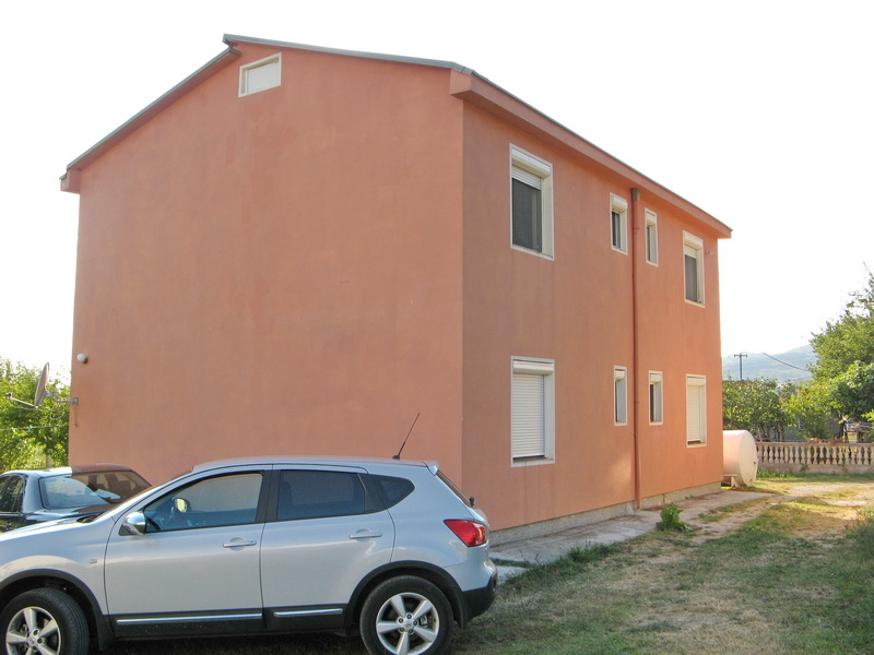 Two-story peach-colored house with shutters on the windows and parking in the yard, Bar, Montenegro.