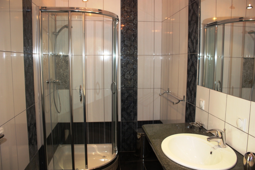Bathroom in an apartment in Bečići, Montenegro: shower cabin, sink with countertop, and black-and-white tiles.