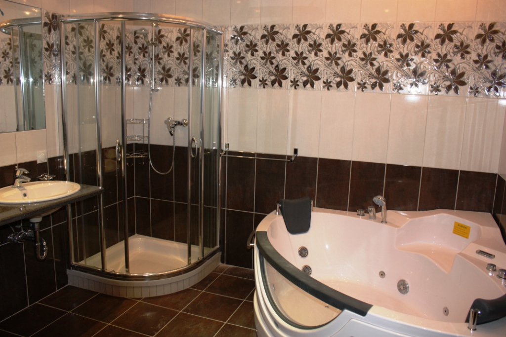 Bathroom in an apartment in Bečići, Montenegro: corner jacuzzi, shower cabin, and tile finish with a floral pattern.