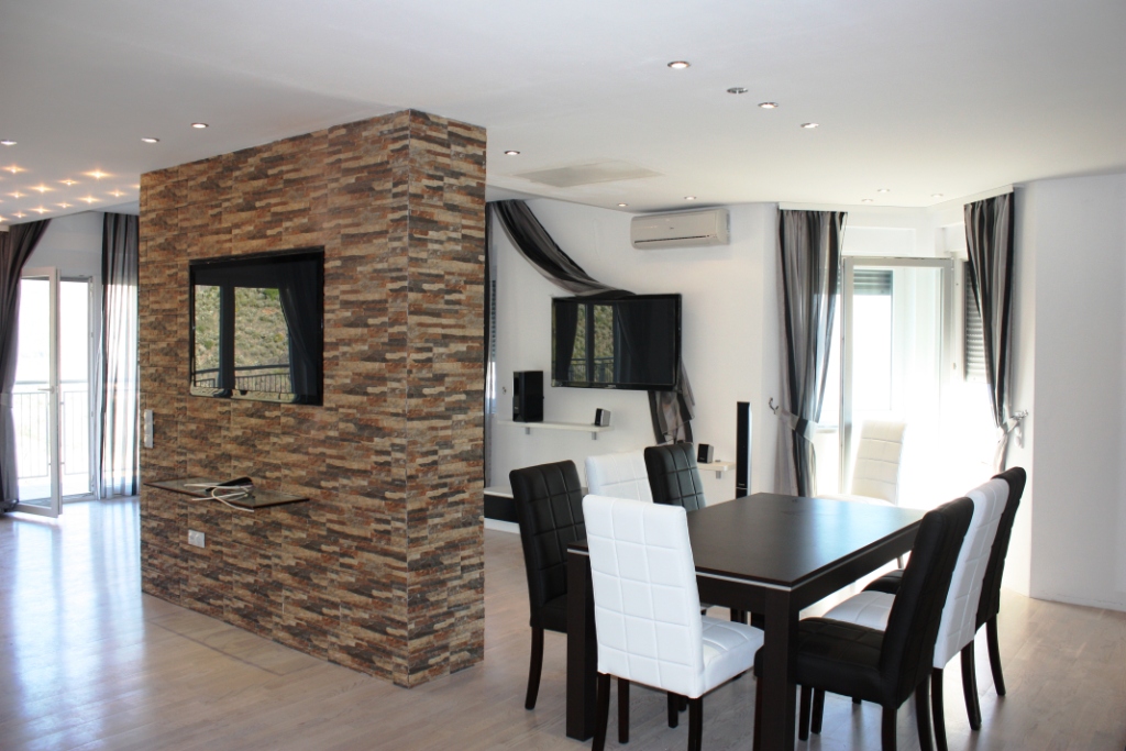 Living room with dining area and stone finishes in an apartment, Bečići, Montenegro: modern furniture and access to the terrace.
