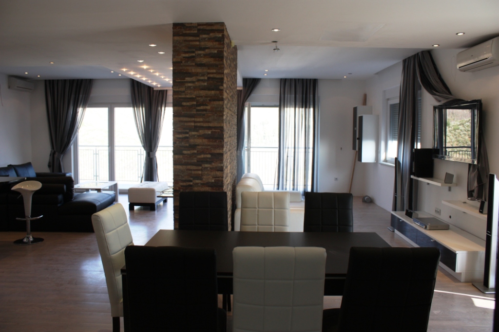 Modern living room in an apartment in Bečići, Montenegro: dining area, leather furniture, and stone finishes.