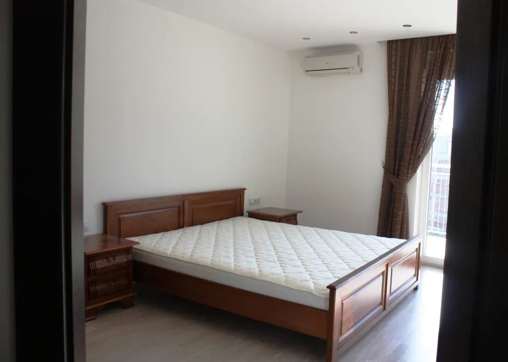 Bedroom featuring a wooden bed frame, mattress, nightstands, and a wall-mounted air conditioner.
