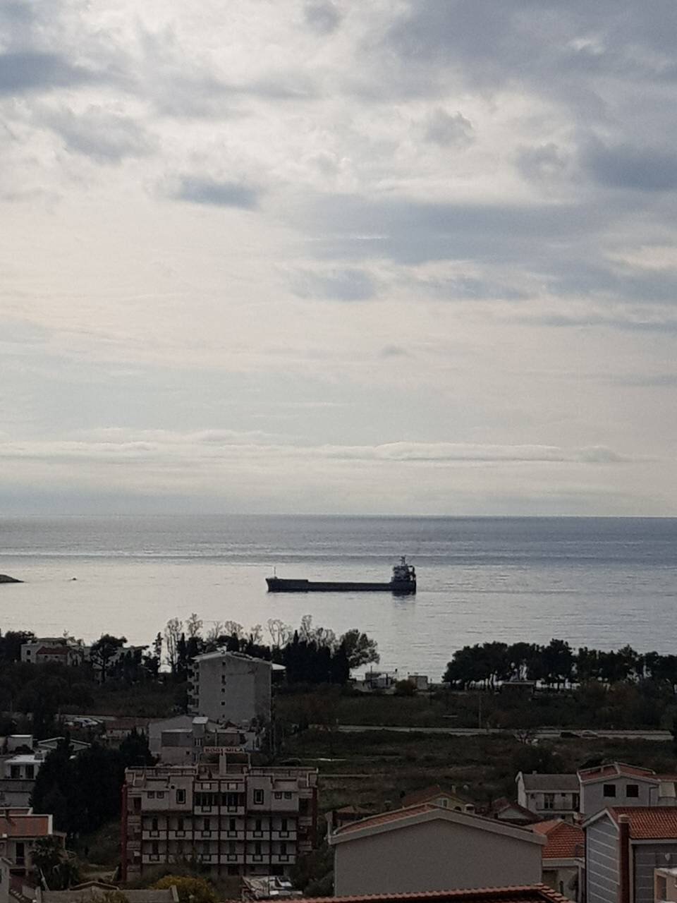 Panoramic sea view and cargo ship from a house in Šušanj, Montenegro, overlooking the coastal development and beach.