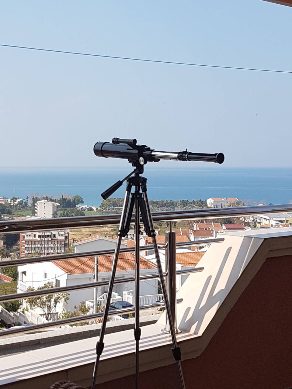 Telescope on the balcony of a house in Shushan, Montenegro, with panoramic views of the Adriatic Sea and cityscapes.