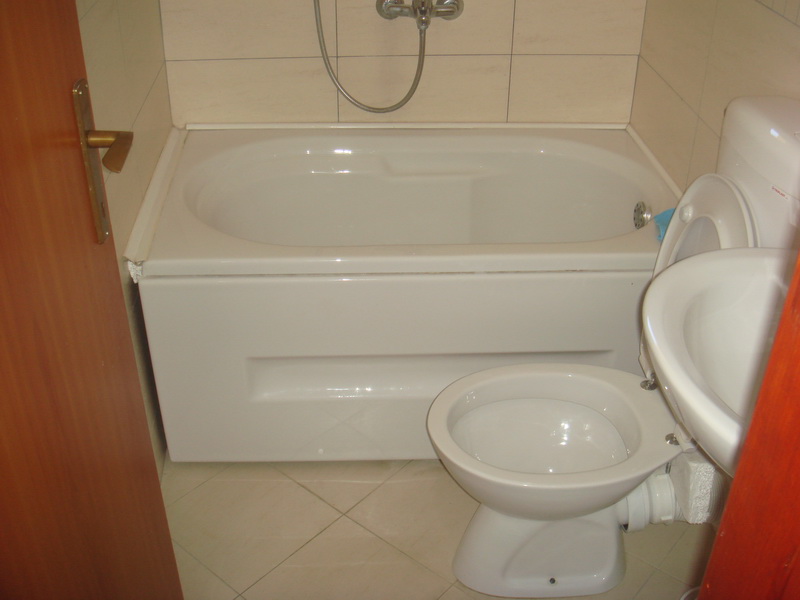 Bathroom in a house in Shushan, Montenegro: white bathtub, plumbing fixtures, and light-colored tiles in the interior of house No. 577.
