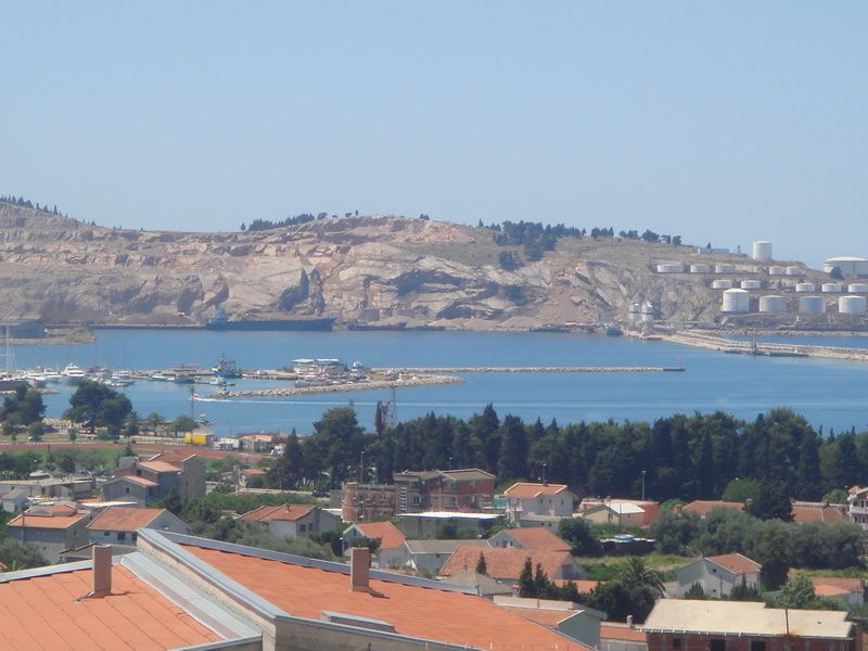 Panoramic view of the sea, port, and mountains from a house in Šušanj, Montenegro: tiled roofs and seascape.