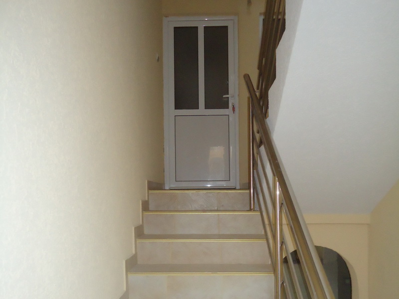 Staircase with metal railings and light finishes in a house in Shushan, Montenegro. Entrance door to the apartment.