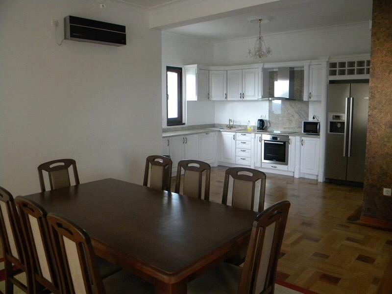 Spacious kitchen-dining room with a white kitchen set and a wooden dining table in a villa in Herceg Novi, Montenegro.