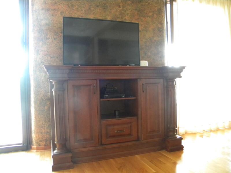 Living room in a villa in Herceg Novi, Montenegro: a classic wooden TV stand against a textured wall.