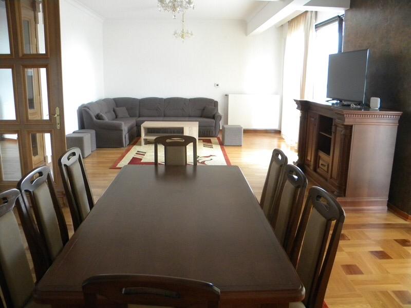 Spacious living room with dining area and a cozy seating corner in a villa in Herceg Novi, Montenegro: wooden furniture and parquet flooring.
