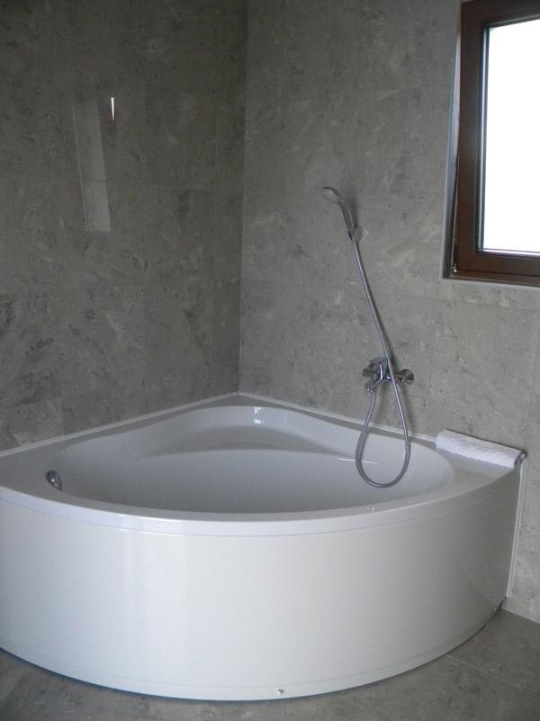 Corner bathtub in a modern bathroom with gray stone finishes in a villa in Herceg Novi, Montenegro.