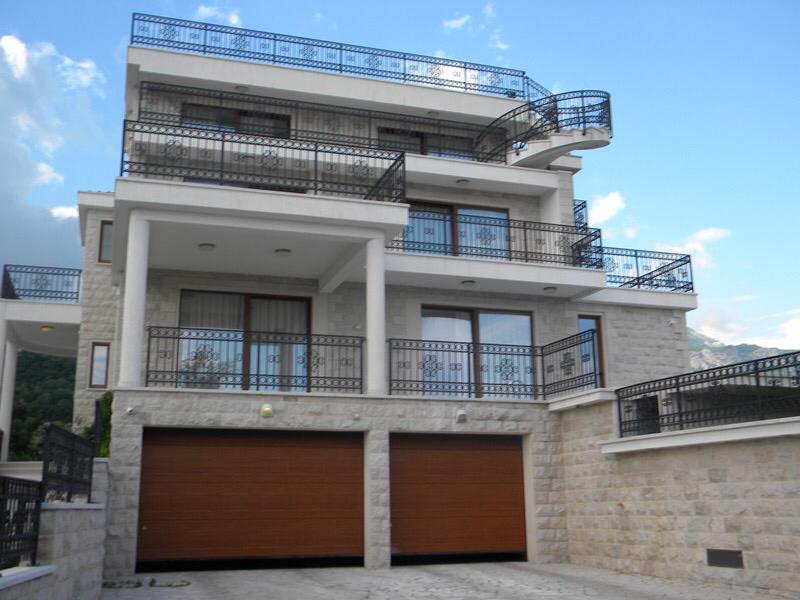 Three-story villa in Herceg Novi, Montenegro: stone facade, terraces with wrought-iron railings, and a two-car garage.