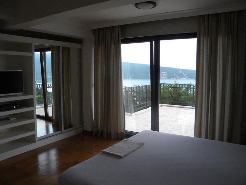 Bedroom in a villa in Herceg Novi, Montenegro: sea view from the terrace, panoramic windows, built-in wardrobe, and parquet flooring.