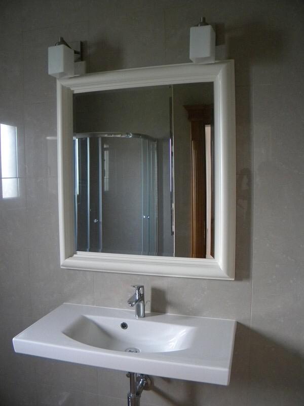Modern bathroom in a villa, Herceg Novi, Montenegro: white sink, framed mirror, and shower cabin.
