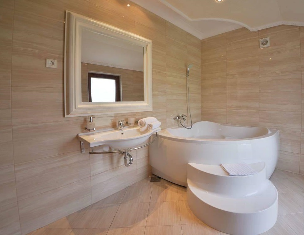 Bathroom with a corner bathtub and beige tiles in a villa in Herceg Novi, Montenegro. Modern interior.