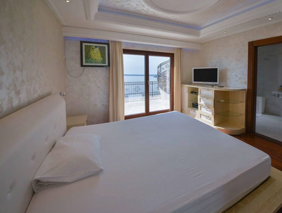 Bedroom in a villa in Herceg Novi, Montenegro: a double bed, TV area, and access to a terrace with panoramic sea views.