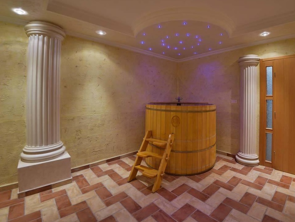 Spa area with a wooden plunge pool and columns in a villa in Herceg Novi, Montenegro. Tiled finish and decorative lighting.