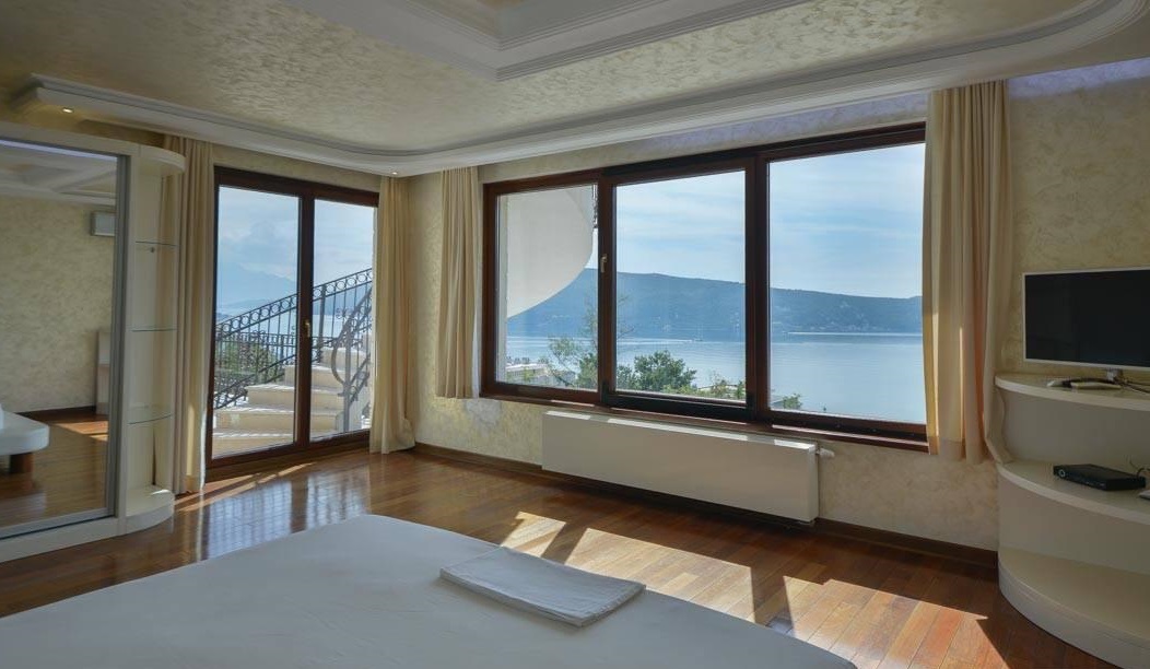 Bedroom in a villa in Herceg Novi, Montenegro: panoramic windows with sea views, parquet flooring, and access to the terrace.