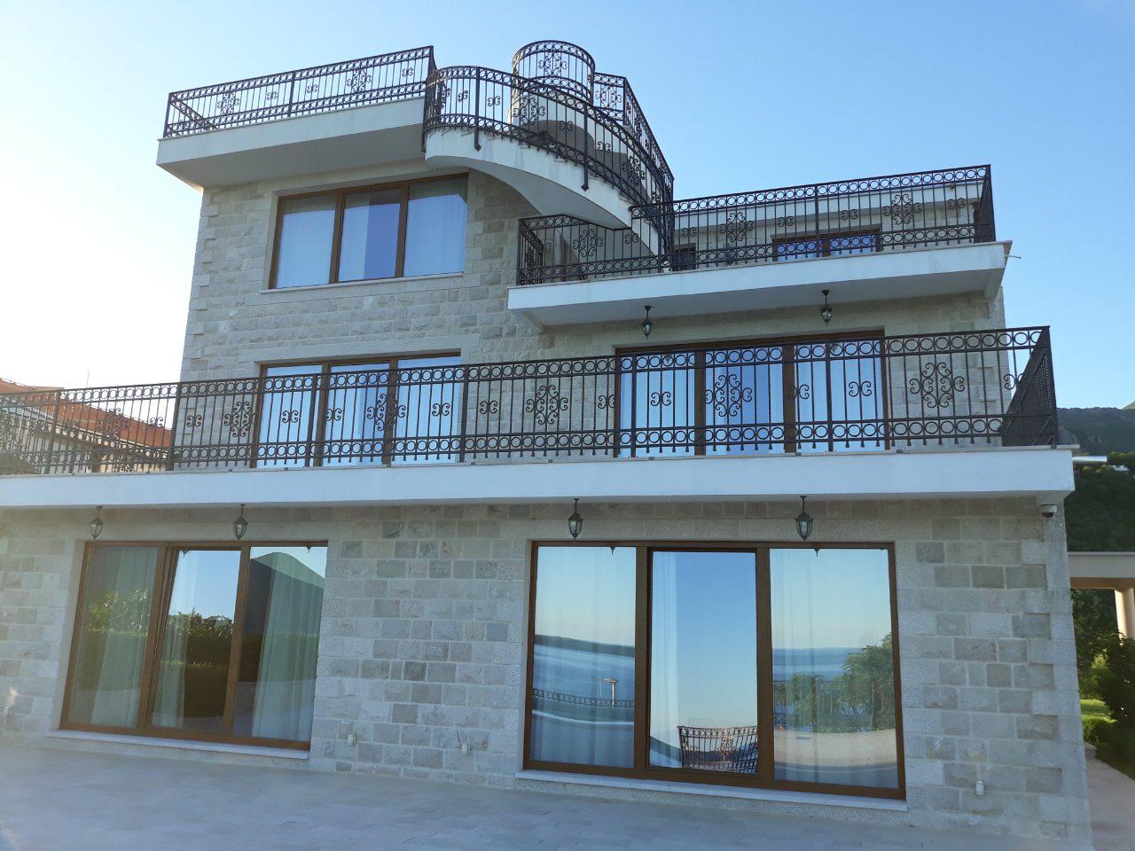 Three-story stone villa in Herceg Novi, Montenegro, with panoramic windows, terraces, and wrought-iron railings.