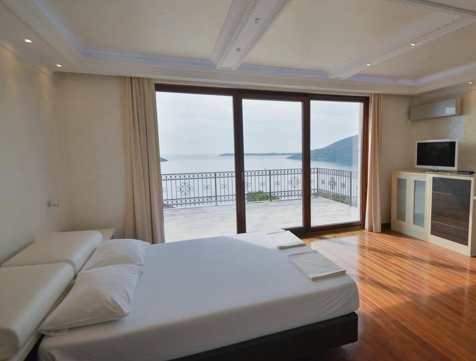 Bedroom with panoramic sea view and terrace in a villa in Herceg Novi, Montenegro: double bed and parquet flooring.