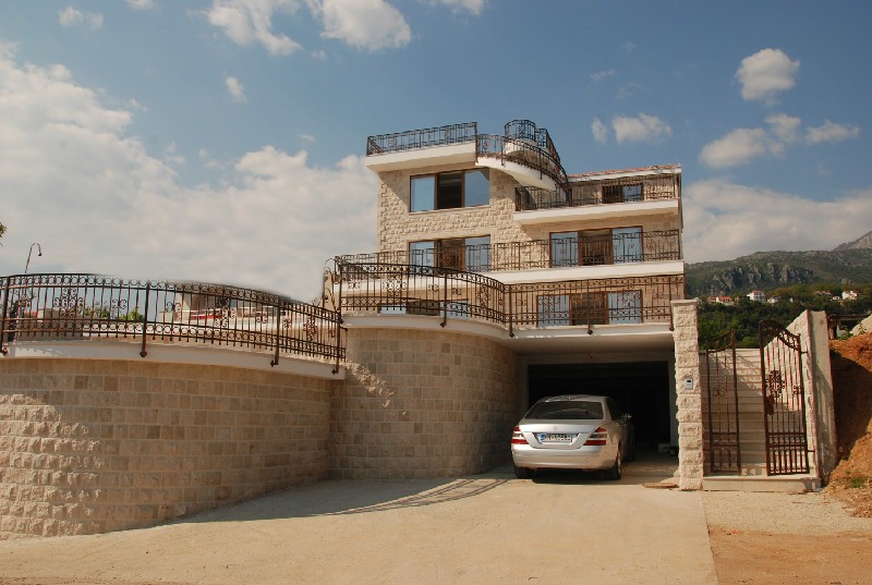 Three-story stone villa with terraces and a garage in Herceg Novi, Montenegro: exterior view of a modern house with wrought iron details.