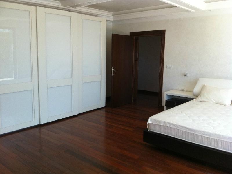 Bedroom featuring a white wardrobe, dark wood flooring, and a bed with a mattress.