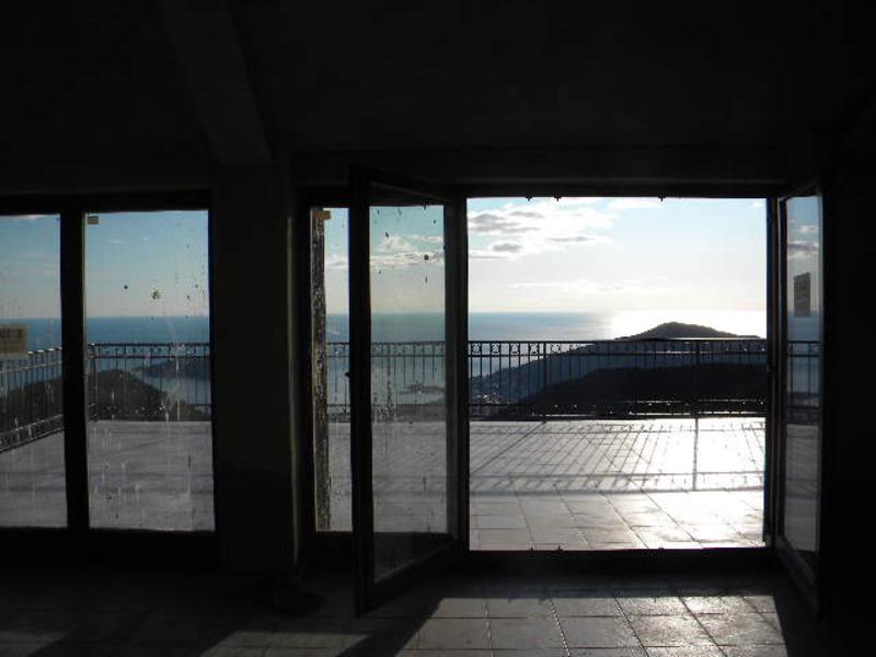 Living room with panoramic access to the terrace and sea view in a house in Budva, Montenegro. Tiled floor, open doors.
