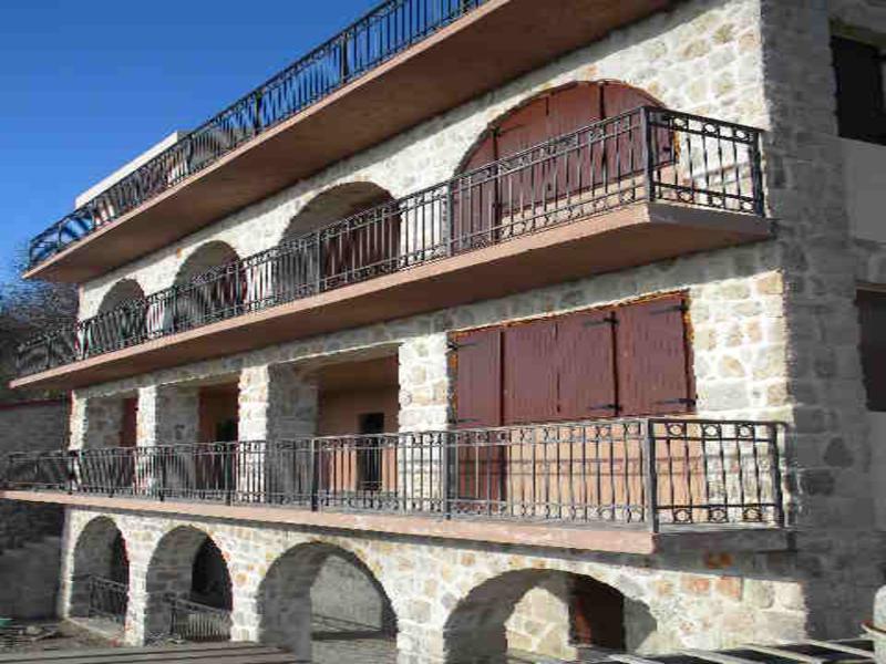 Three-story Mediterranean-style house with stone finishes and wrought-iron balconies in Budva, Montenegro.