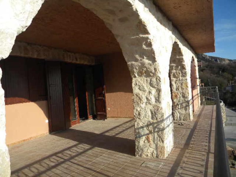 Spacious terrace with stone arches in a house in Budva, Montenegro, mountain view and access from the house through wooden doors.