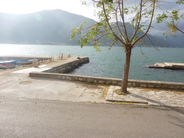 Sea view and private pier by the house in Kumbor, Montenegro: waterfront with a tree and mountain scenery in the background.