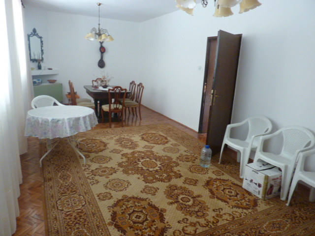 Living room in a house in Kumbor, Montenegro: dining area, parquet floor, classic rug, and light-colored furniture.