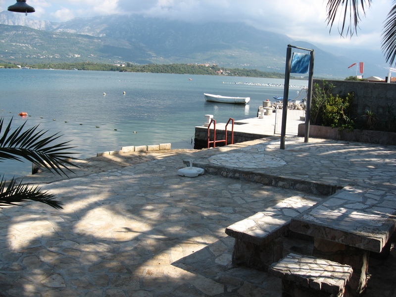 Terrace with a stone table by the sea in Tivat, Montenegro: private water access, pier, and mountain views.